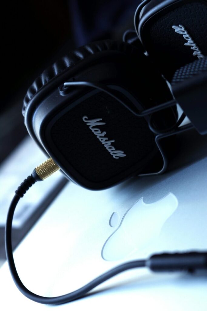 Close-up of Marshall headphones resting on a sleek laptop, emphasizing premium audio equipment.